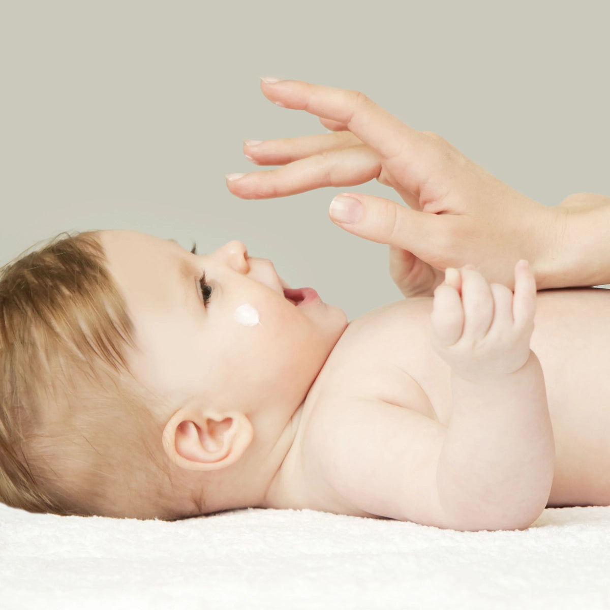 Mutter cremt die Wange ihres Babys mit vujo Baby Gesichtscreme ein
