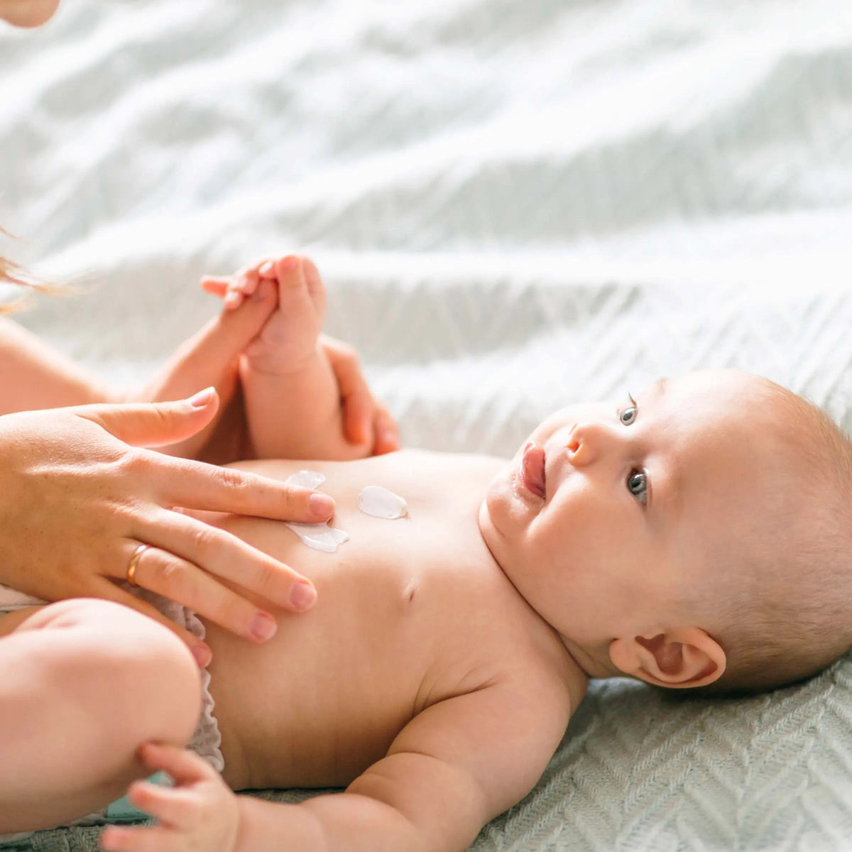 Mutter cremt die Brust ihres Babys mit vujo Baby Körperlotion ein