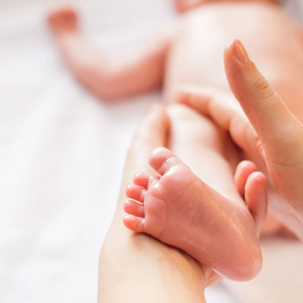Mutter massiert die Füße ihres Babys mit parfümfreiem vujo Baby Öl