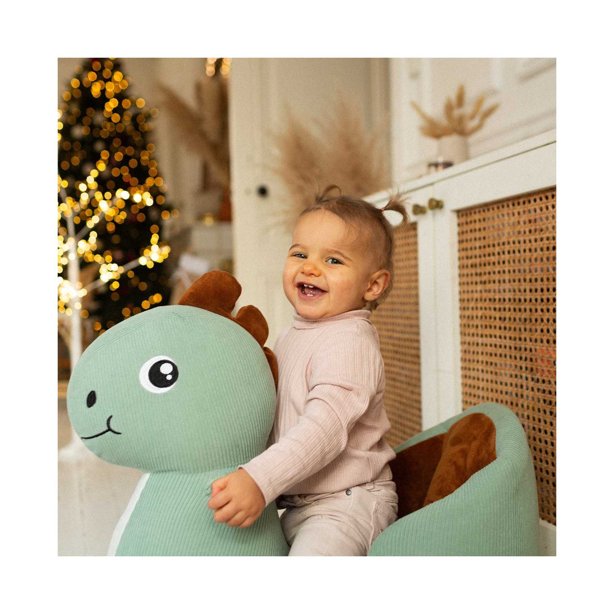 Kind auf dem Schaukeltier Dinosaurier Diplododo am Weihnachtsbaum