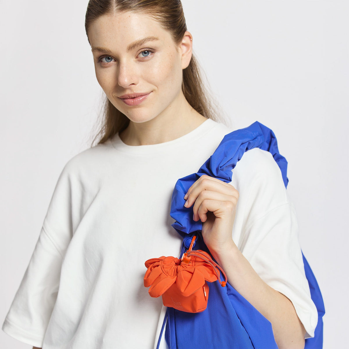 GOT BAG Anemone Charm Taschenanhänger in Korallenrot, von einer Frau an einer Tasche getragen