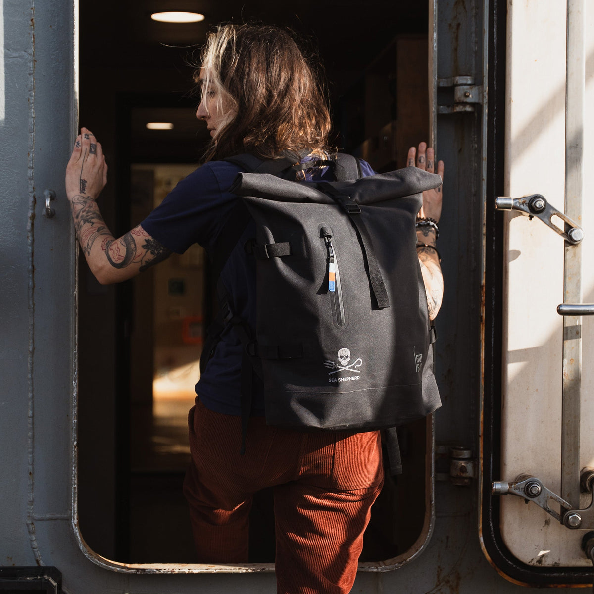 GOT BAG Rolltop 2.0 Rucksack Sea Shepherd Edition in Schwarz, von einer Frau auf dem Rücken getragen