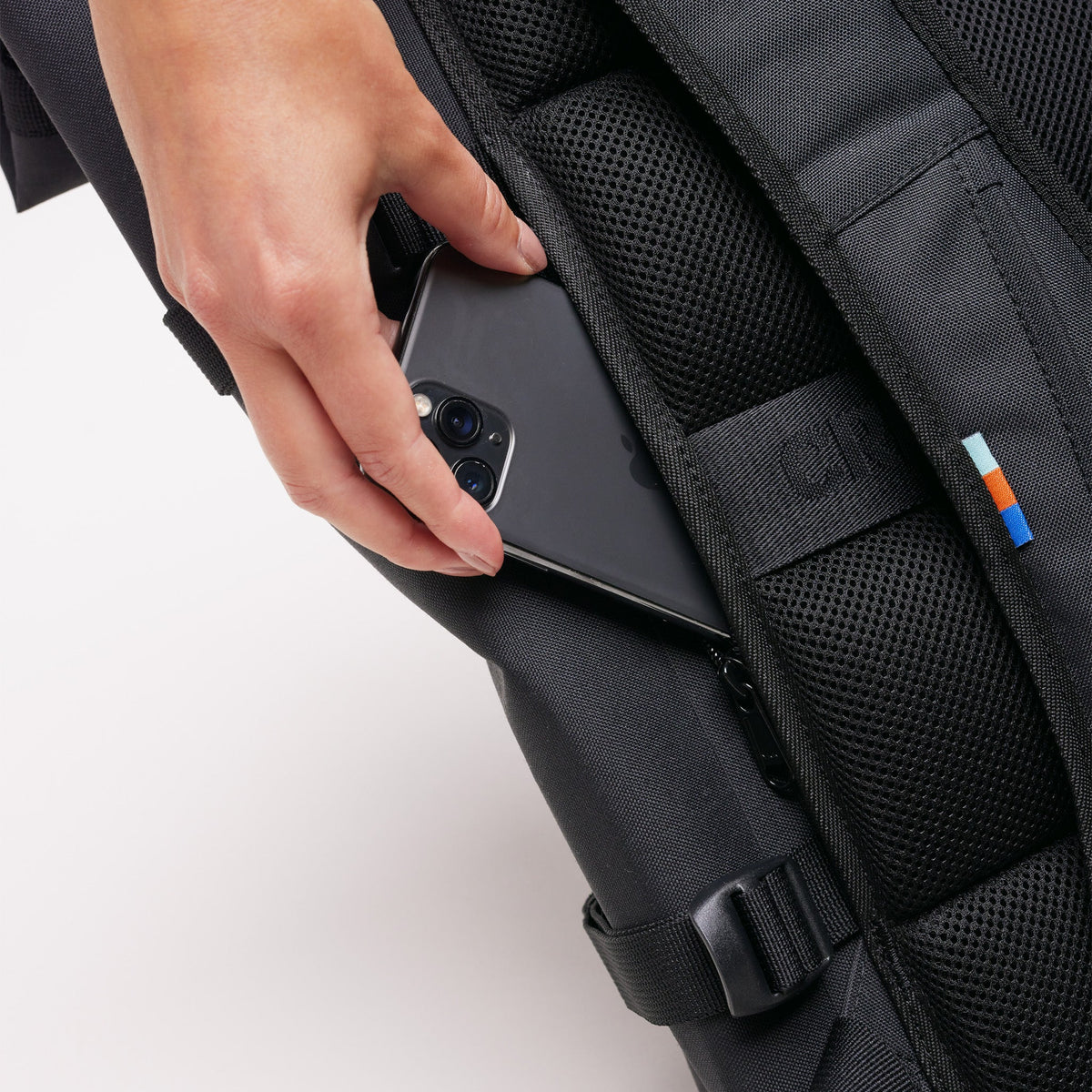 GOT BAG Rolltop 2.0 Rucksack Sea Shepherd Edition in Schwarz, eine Frau steckt ein Smartphone in die Seitentasche