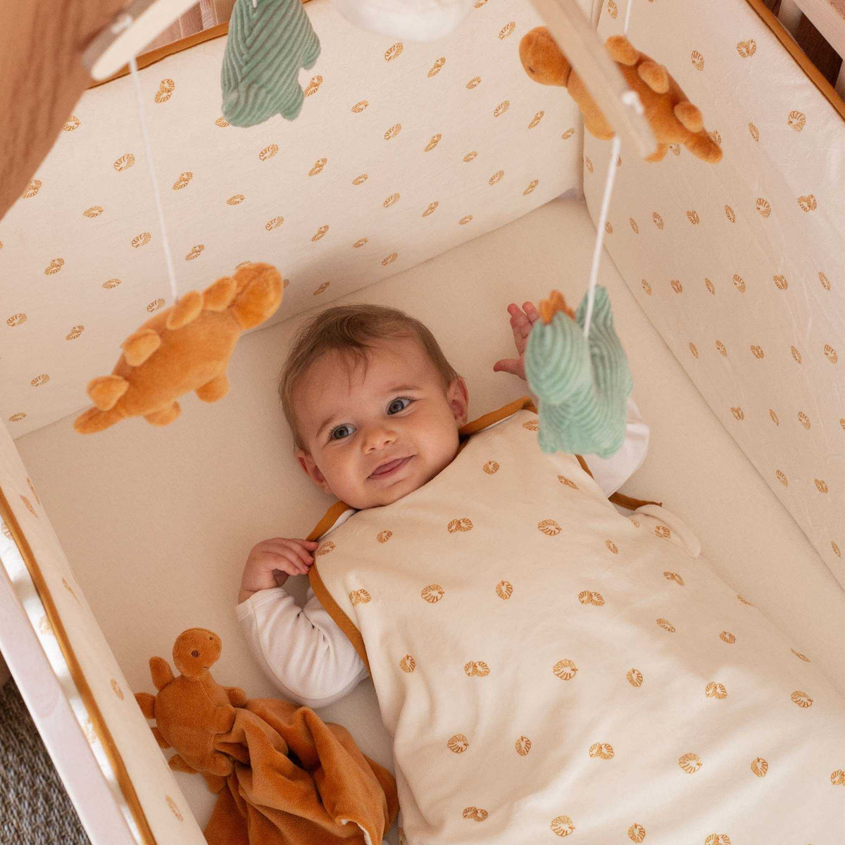 Baby im Gitterbett hört die Melodie des Musikmobiles Diplododo